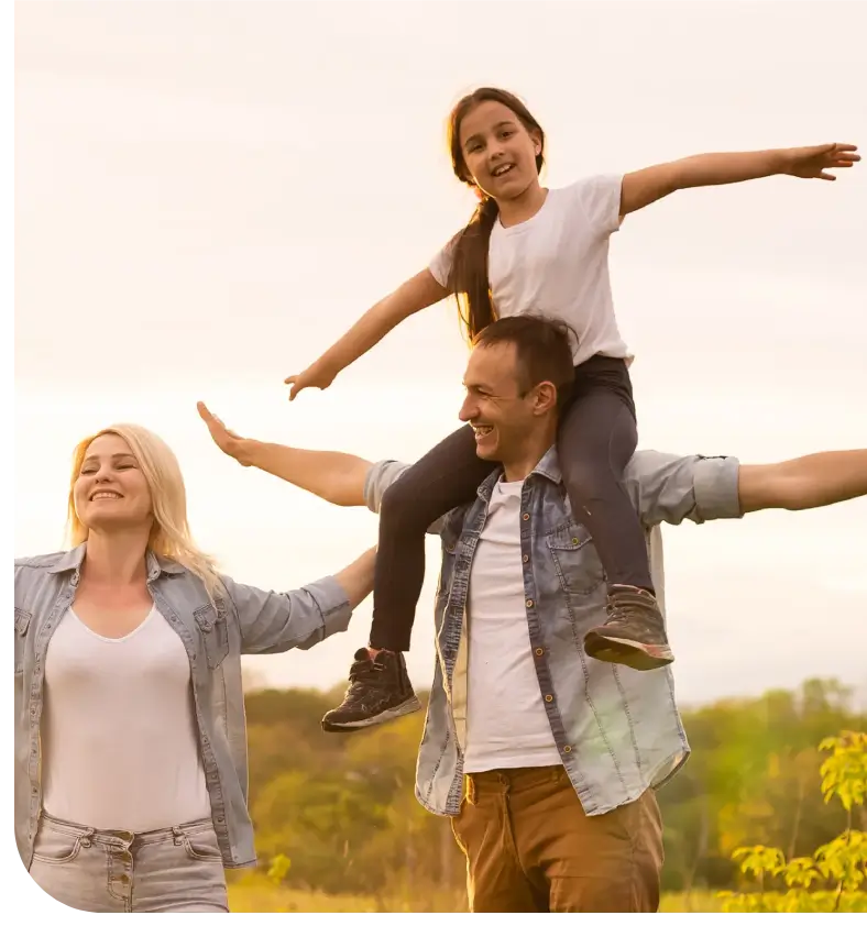 Family enjoying outdoors with child on father's shoulders.
