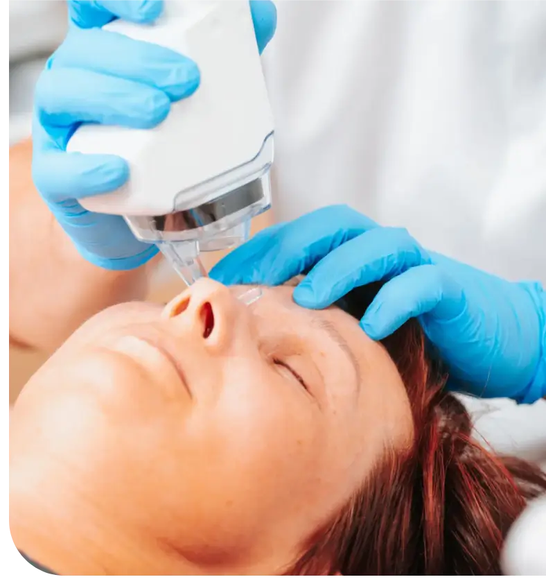 Woman receiving a facial treatment with a handheld device.