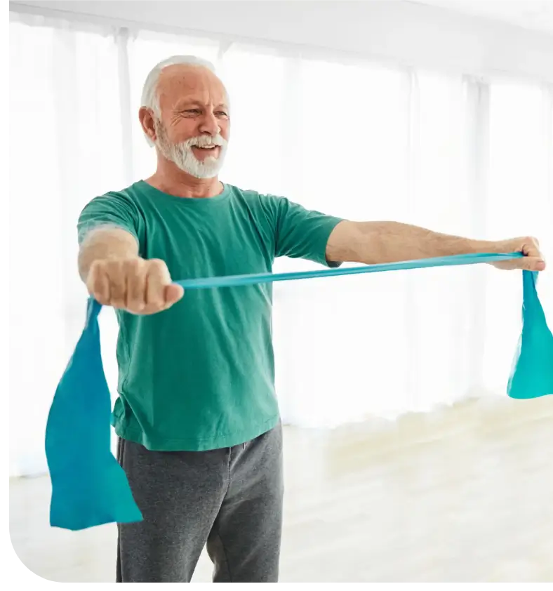 An elderly man exercising with a resistance band indoors.