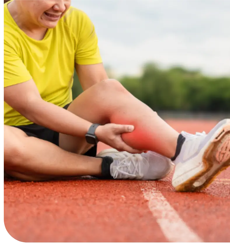 Person holding their painful swollen ankle on a running track.
