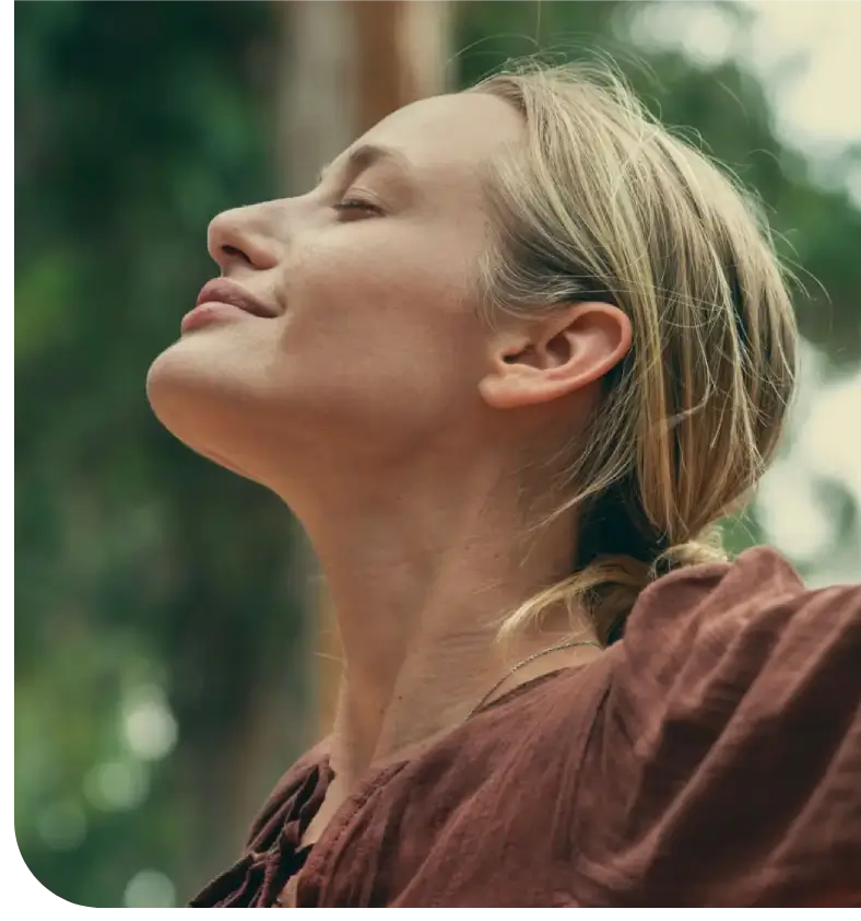 Woman enjoying a peaceful moment outdoors with eyes closed.